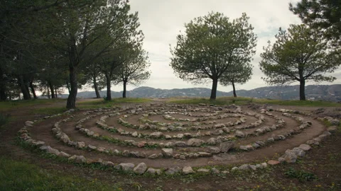 Man made stone labyrinth in forest clearing with mountain backdrop Stock Footage 328337768