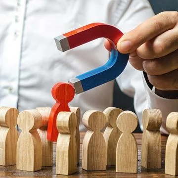 A man with a magnet pulls a red human figure out of crowd. Identify disloyal, Stock Photos