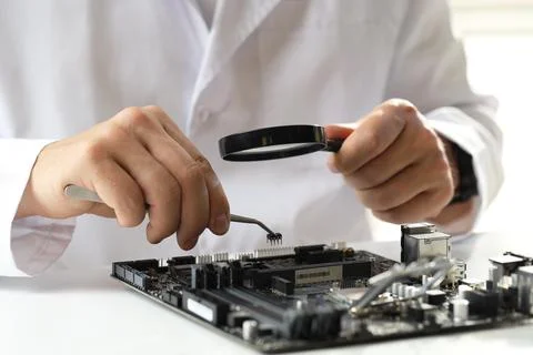 Man with magnifying glass installing computer chip onto motherboard at whit.. Stock-Fotos