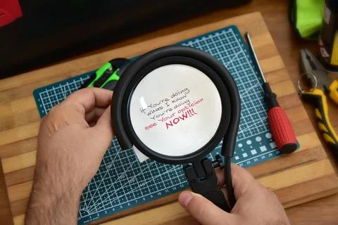 Man magnifying small text on a note that advises him to visit an ophthalmologist Stock Photos