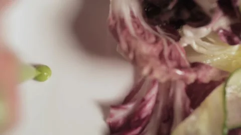 A man make a big fat dot of green sauce on a white plate with salad Stock Footage 136056304