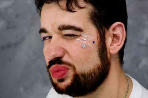 A man with make up blinks - He is red lips and beard - transgender. Stock Photos