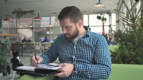 Man make notes in calendar, look at camera, cafe, portrait, steadycam Vídeo Stock 72951776
