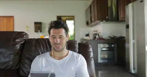 Man Make Online Video Call Using Tablet Computer Sit On Coach In Living Room Stock Footage