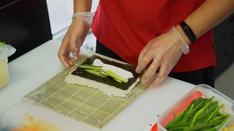 Man make sushi rolls on a mat of bamboo or makisu on white table in the kitchen. Stock Footage 119979149