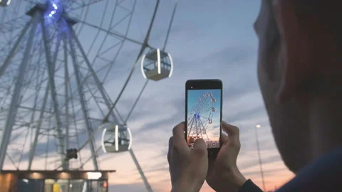 Man make video of ferris wheel at sunset using camera on mobile phone Stock Footage 219918143