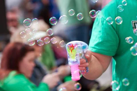 Man makes bubbles with bubble pistol at parade Stock Photos