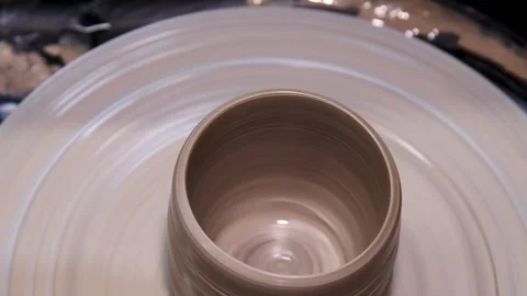 Man makes a clay pot or vase on a potter's wheel Stock Footage 324856077