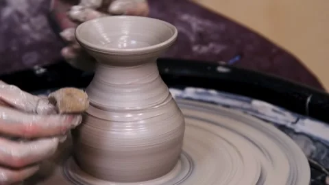 Man makes a clay pot or vase on a potter's wheel Stock Footage 324856100