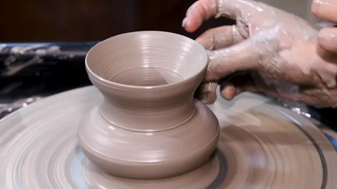 Man makes a clay pot or vase on a potter's wheel Vidéo 339765061