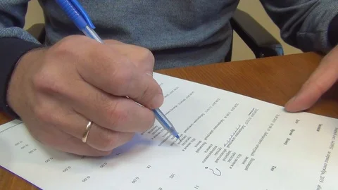 A man makes corrections in entries on a sheet of white paper with a ballpoint pe Stock Footage 118389107