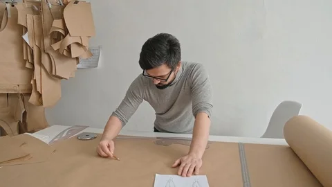Man makes a dress pattern, standing behind the table, fashion business Video stock 121928334