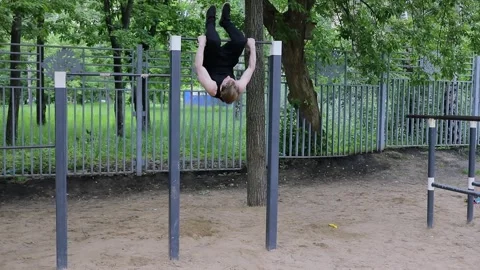Man makes exercises on bar among trees. Slow motion Stock Footage 276377663