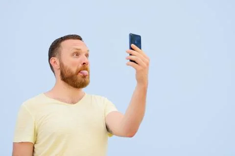 Man makes faces in a funny and humorous phone shows a language, an advertisin Stock Photos