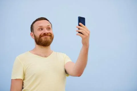 Man makes faces in a funny and humorous phone shows a language, an advertisin Stock Photos