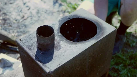 A man makes a fire in a rusty outdoor stove with paper. Stock Footage 136192259
