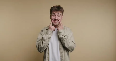 Man makes funny faces and smiles against a plain background in a series of .. Stock-Footage 331989860