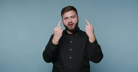 Man makes gesture while wearing black shirt against blue background in indo.. Vídeos de archivo 326798736