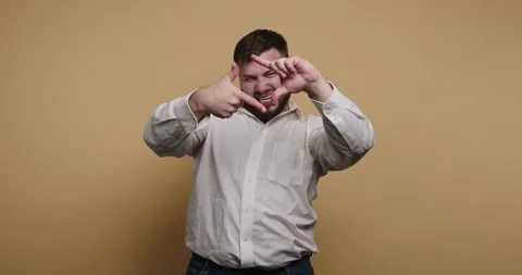 Man makes hand gestures in front of plain colored background while showing .. 스톡 동영상 326797409