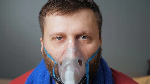 Man makes inhalation using nebulizer. He is looking at camera. Slow motion and Видео 123275660