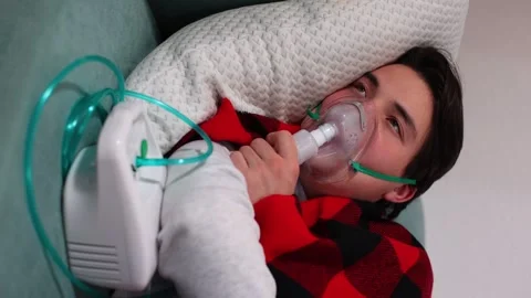 Man makes inhalation using nebulizer.Lying on the sofa.Vertical video 스톡 동영상 262852533