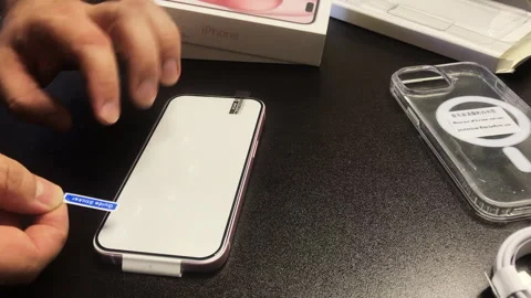 The man makes the installation of protective glass for iPhone 15. Fixes it .. Stock Footage 277545990