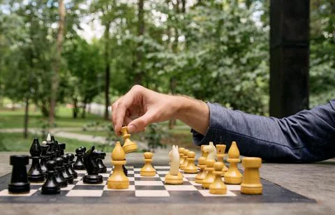 A man makes a move with a chess piece of a white queen, side view of the game Stock Photos