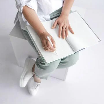 A man makes notes with a pen in a white large notebook. White background, top Stock Photos