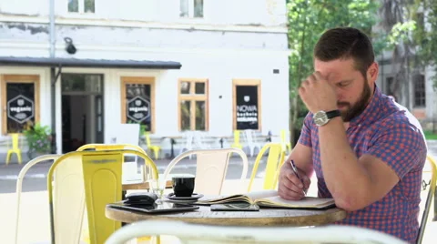 Man makes notes from smartphone to notebook in cafe, slider shot, left 库存影片 67629445