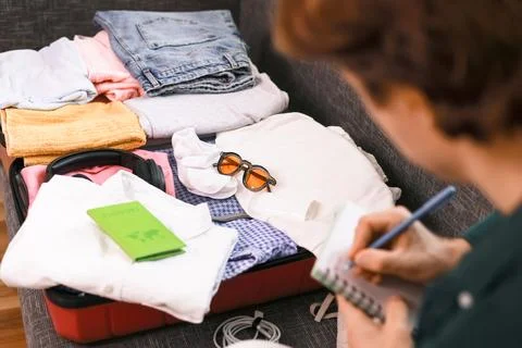 Man makes a packing list for summer travel preparation. An open suitcase ho.. Stock Photos