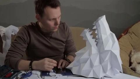 Man makes paper wolf's head next to his retriever Stock Footage 72750546