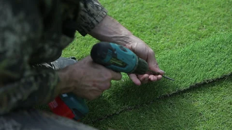 Man makes a path of artificial grass Stock Footage 64008398