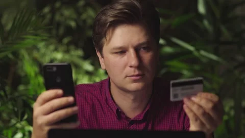 A man makes purchases using a phone and a bank card Stock Footage 149028136