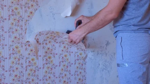 Man makes renovation removing wallpapers from wall using spatula, hands closeup. Stock Footage 124947759