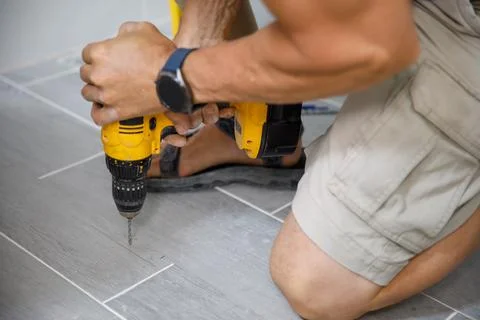 A man makes repairs in the bathroom using a puncher Stock Photos