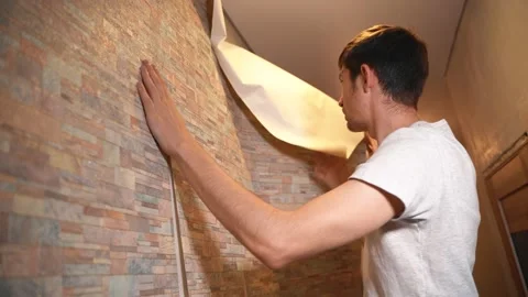A man makes repairs in his house, neatly gluing wallpaper Video stock 146040984