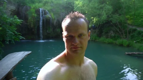 A man makes a selfie on the background of a tropical waterfall. Slow motion Stock Footage 90661251