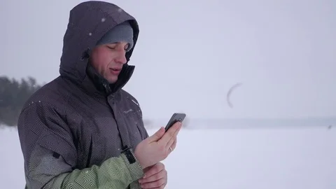 Man makes selfie, choose a convenient angle, against the backdrop of snow Stock Footage 71314873