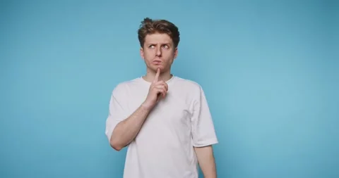 Man makes shushing gesture in a simple blue background while showing differ.. 库存影片 331990886