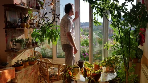 Man Makes Step Outdoor on a Terrace Pot Plants Are Decorating the Room Sun Rays Stock Footage 71636552
