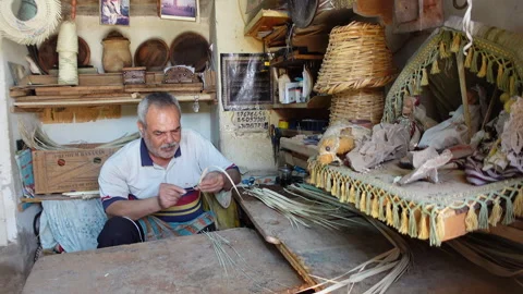 Man makes straw baskets in workshop in historic medina of Tozeur in Tunisia Stock Footage 328633261