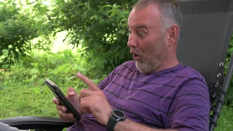 The man makes a surprised face as he looks at the phone screen 動画素材 245159585