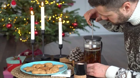 A man makes tea in front of a Christmas tree Stock Footage 167325076