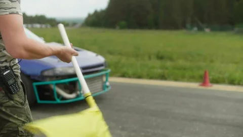 Man makes three swing with a yellow flag and race car breaks off from the start Stock Footage 129920982