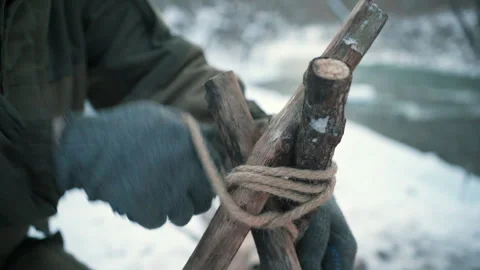 A man makes a tripod for a fire Stock Footage 266700344