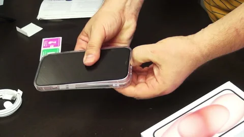 A man makes a unpacking case for iPhone 15. Trys the silicone cover on a sm.. Stock Footage 277546185