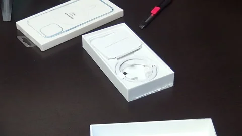 A man makes the unpacking of a modern smartphone. Considers the contents of.. Stock Footage 277546456