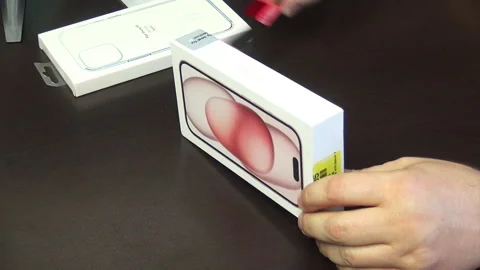 A man makes the unpacking of a modern smartphone. Box with iPhone 15. Stock Footage 277546557