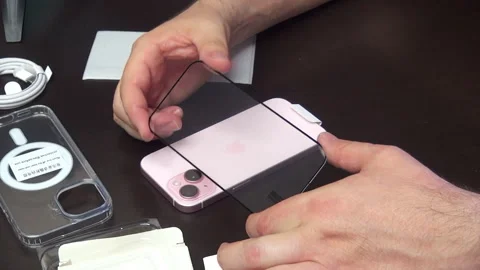 A man makes the unpacking protective glass for iPhone 15. Stock Footage 277546145