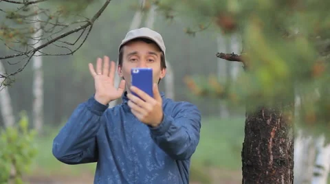 A man makes a video call by phone near a tree in the forest. Early morning Stock Footage 64597673